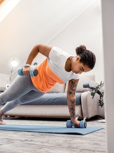Woman doing at-home workouts using weights in living room