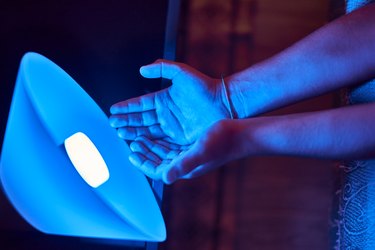 A person's hands next to a phototherapy light as a treatment for psoriasis