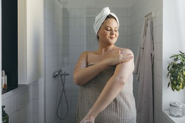 a woman applying lotion after a shower, as a natural remedy for sunburns