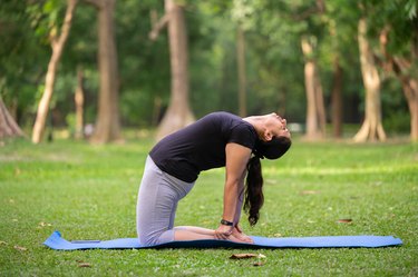 Active person doing camel pose or Ustrasana, a great yoga for sitting move, at a park