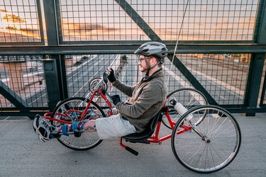 Person handcycling outside on a bridge during sunset.