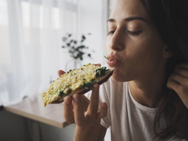 closeup of a young caucasian woman eating avocado toast before exercise