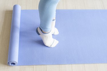 Adult performing calf raises with light blue leggings on blue yoga mat.