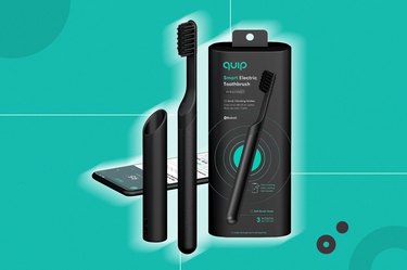A black electric toothbrush with its packing and accessories, with a blue background